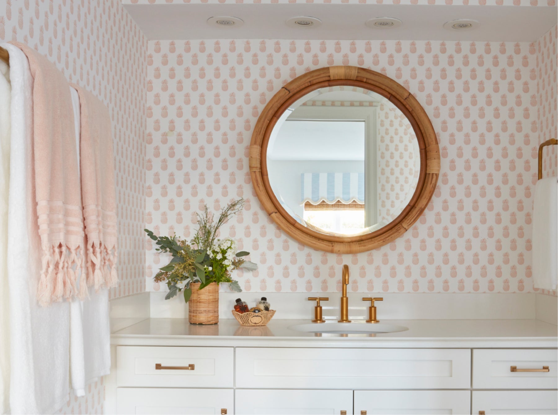 A bathroom set of cabinets with a sink on top and a circular mirror with a wooden outline.